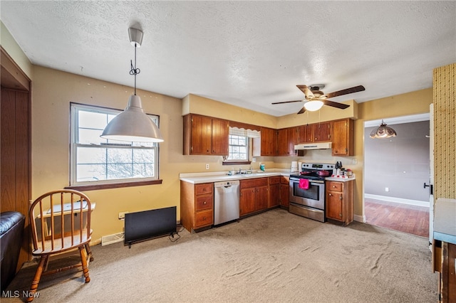 kitchen featuring under cabinet range hood, dishwashing machine, brown cabinets, and stainless steel range with electric stovetop