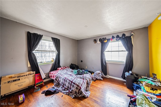 bedroom with baseboards, a textured ceiling, and hardwood / wood-style floors