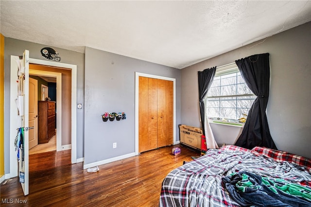 bedroom with wood finished floors, baseboards, a closet, and a textured ceiling