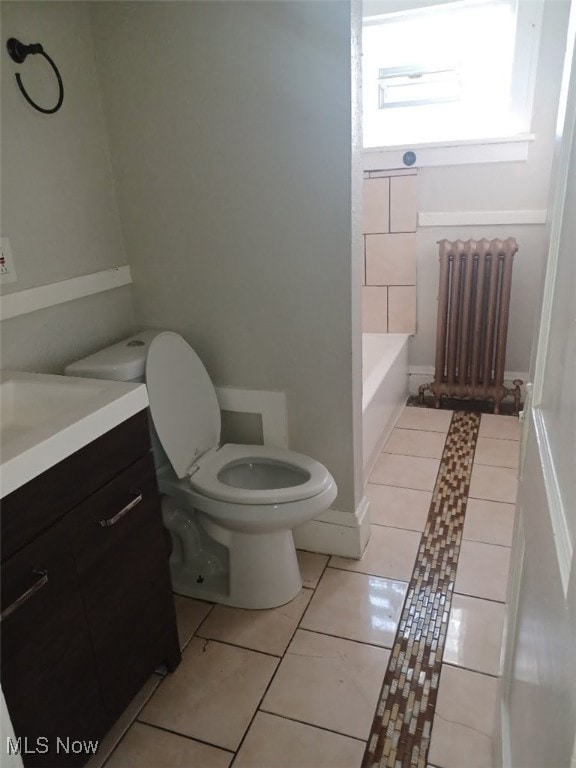 full bath featuring tile patterned floors, toilet, a tub to relax in, radiator, and vanity