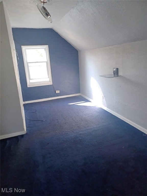 additional living space with lofted ceiling, baseboards, and a textured ceiling