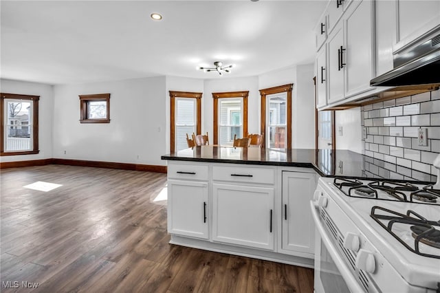 kitchen featuring dark wood-type flooring, white cabinetry, a peninsula, baseboards, and white gas range