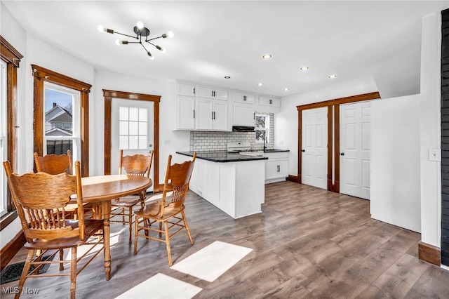 kitchen featuring a notable chandelier, dark countertops, a peninsula, exhaust hood, and range