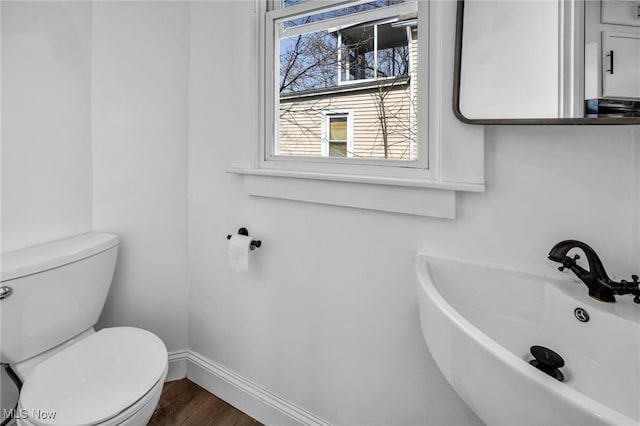 bathroom with a sink, baseboards, toilet, and wood finished floors