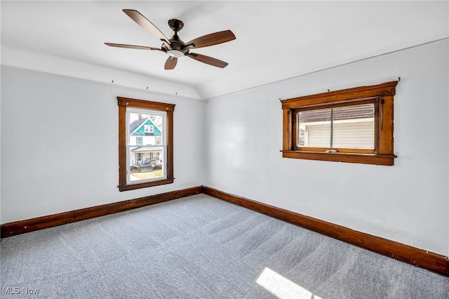 empty room with baseboards, a ceiling fan, lofted ceiling, and carpet flooring