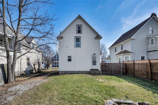 back of property with a yard, a fenced backyard, and entry steps