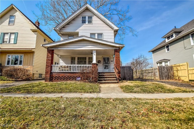 view of front facade with a porch, a front yard, and fence