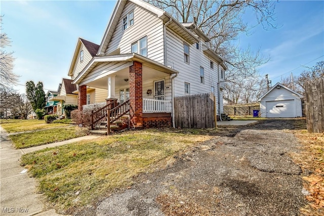 view of front of property with an outbuilding, fence, driveway, covered porch, and a detached garage