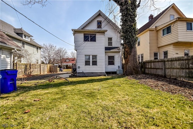 back of property featuring a lawn, central AC unit, and fence