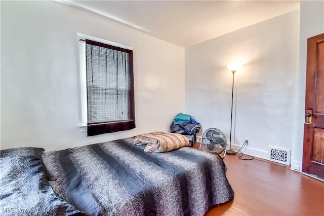 bedroom featuring visible vents, baseboards, and wood finished floors