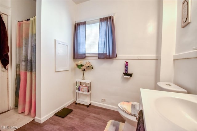 bathroom featuring toilet, curtained shower, wood finished floors, baseboards, and vanity