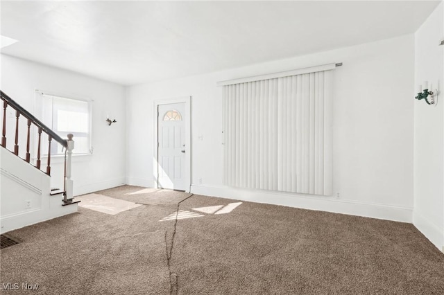 carpeted foyer entrance with stairway and baseboards