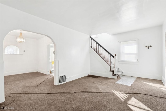 foyer entrance with stairs, baseboards, arched walkways, and carpet floors