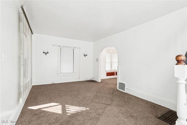 unfurnished bedroom with arched walkways, visible vents, baseboards, and carpet floors