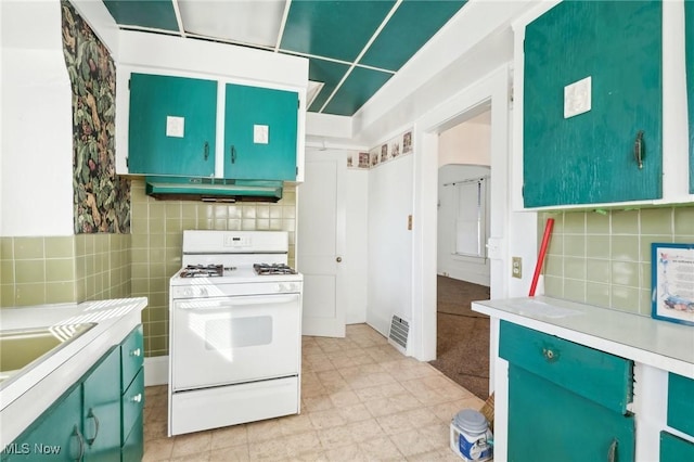 kitchen featuring visible vents, under cabinet range hood, gas range gas stove, tasteful backsplash, and light countertops