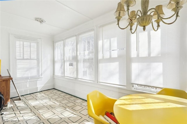 sunroom / solarium featuring a healthy amount of sunlight and a chandelier