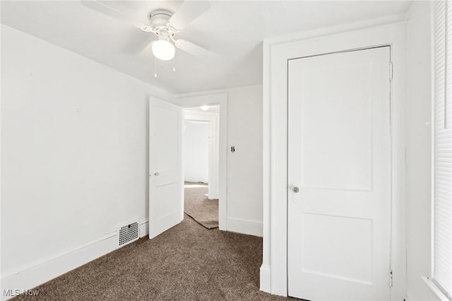 unfurnished bedroom with visible vents, ceiling fan, baseboards, and dark colored carpet