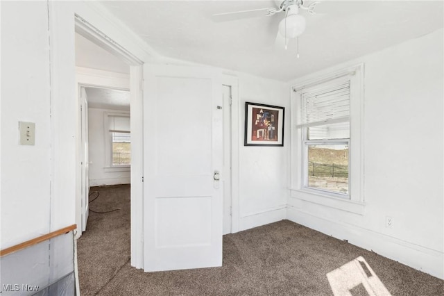 empty room featuring a ceiling fan and carpet