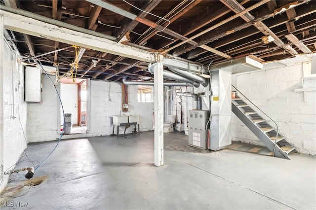 basement featuring stairs, heating unit, and a sink