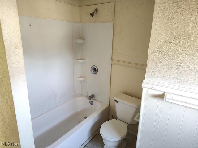 full bathroom with toilet, a textured wall, and shower / bath combination