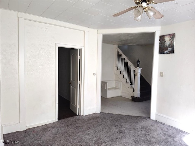 empty room featuring stairway, baseboards, carpet floors, and ceiling fan