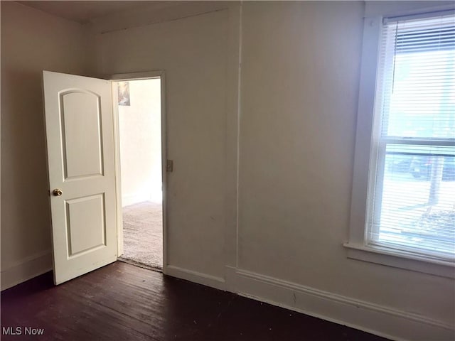 unfurnished room featuring plenty of natural light, baseboards, and dark wood-style flooring