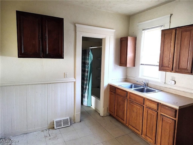 kitchen with light countertops, brown cabinets, visible vents, and a sink