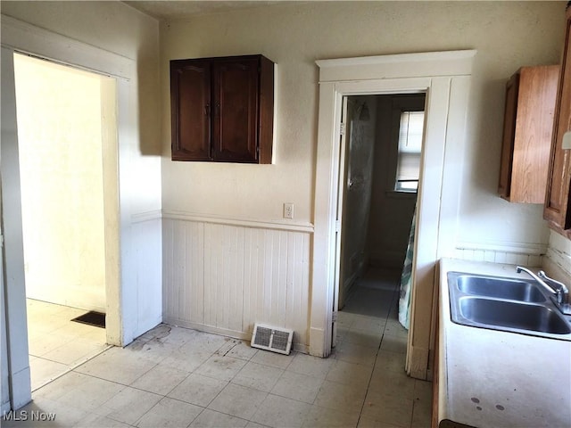 kitchen with dark brown cabinetry, visible vents, light countertops, and a sink