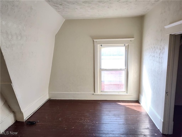 bonus room with baseboards, vaulted ceiling, a textured wall, a textured ceiling, and wood-type flooring