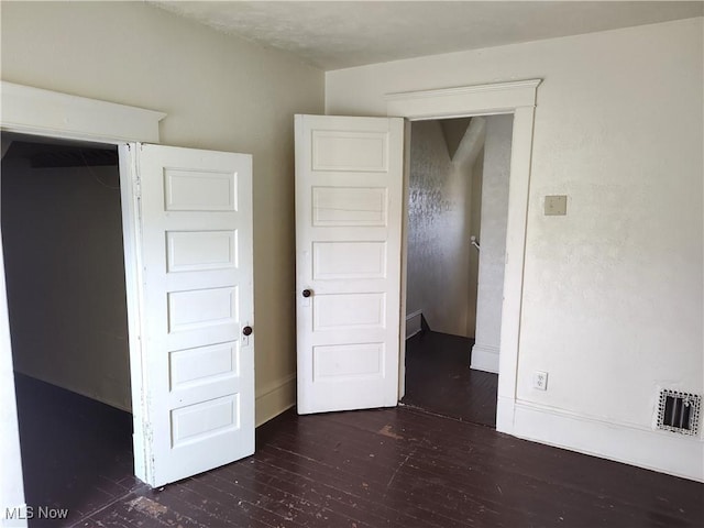 unfurnished bedroom featuring visible vents, dark wood-type flooring, and baseboards