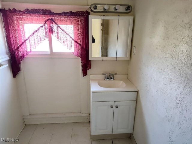 bathroom with vanity, a textured wall, and tile patterned flooring