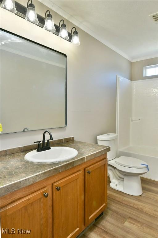 full bath with visible vents, toilet, wood finished floors, crown molding, and vanity