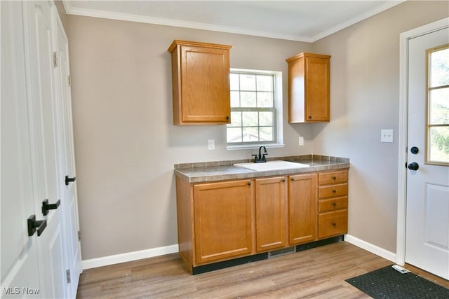 kitchen with tile counters, light wood-style flooring, baseboards, and a sink