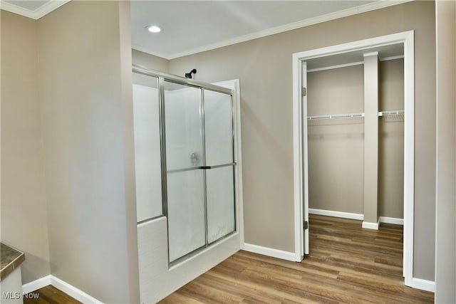 bathroom with a shower stall, crown molding, baseboards, and wood finished floors