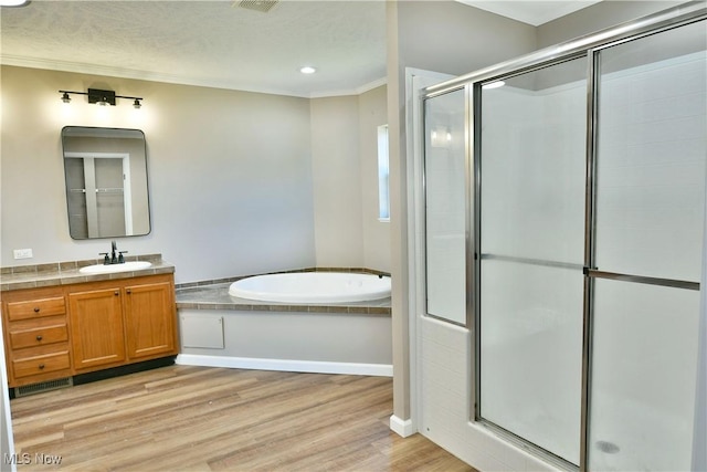 full bathroom with vanity, wood finished floors, a stall shower, crown molding, and a bath