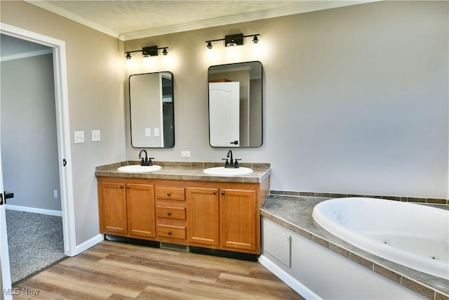 full bath featuring a whirlpool tub, ornamental molding, wood finished floors, and a sink