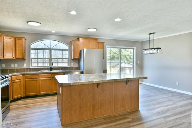 kitchen featuring a wealth of natural light, a kitchen island, appliances with stainless steel finishes, and a sink