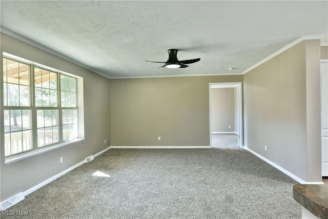 carpeted empty room featuring visible vents, baseboards, ornamental molding, ceiling fan, and a textured ceiling