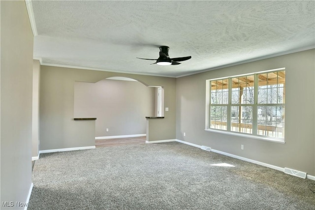 spare room with visible vents, arched walkways, carpet, and ceiling fan