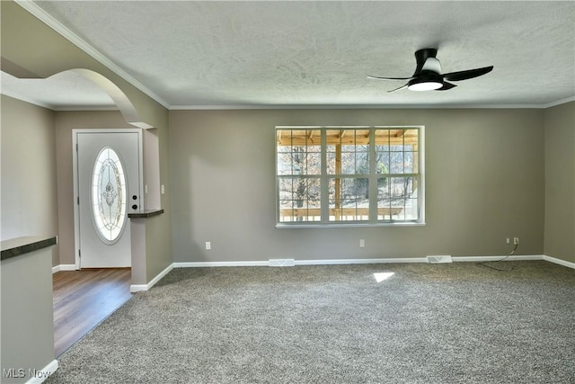 carpeted foyer entrance with baseboards, arched walkways, a textured ceiling, and a ceiling fan