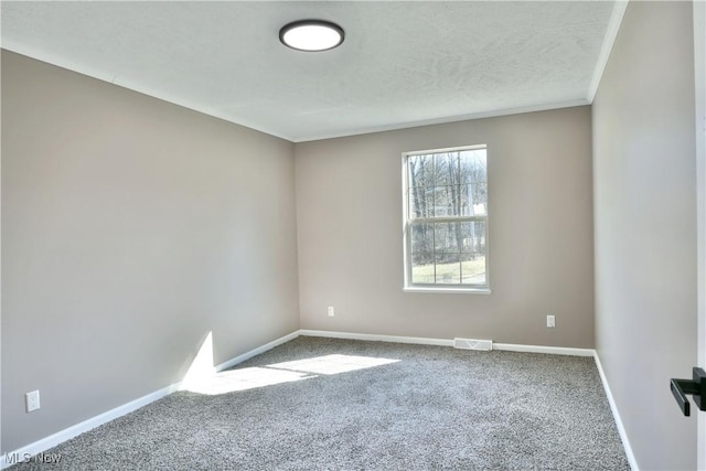 carpeted spare room with baseboards, visible vents, and ornamental molding