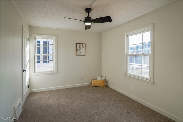 carpeted empty room featuring visible vents, a ceiling fan, baseboards, and ornamental molding