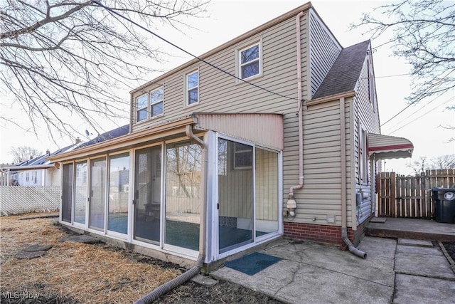 back of house featuring a patio, fence, a sunroom, and a shingled roof