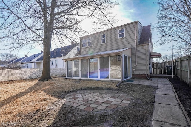 rear view of property with a patio, a fenced backyard, and a sunroom