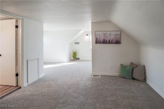 additional living space with visible vents, carpet floors, lofted ceiling, and baseboards