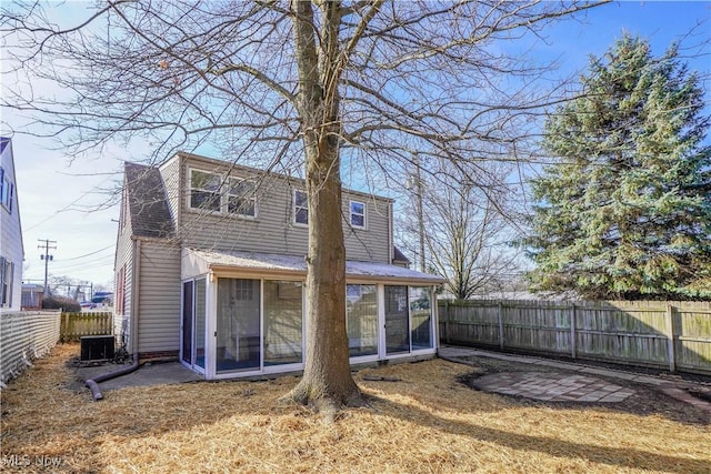 back of house featuring central air condition unit, a fenced backyard, and a sunroom