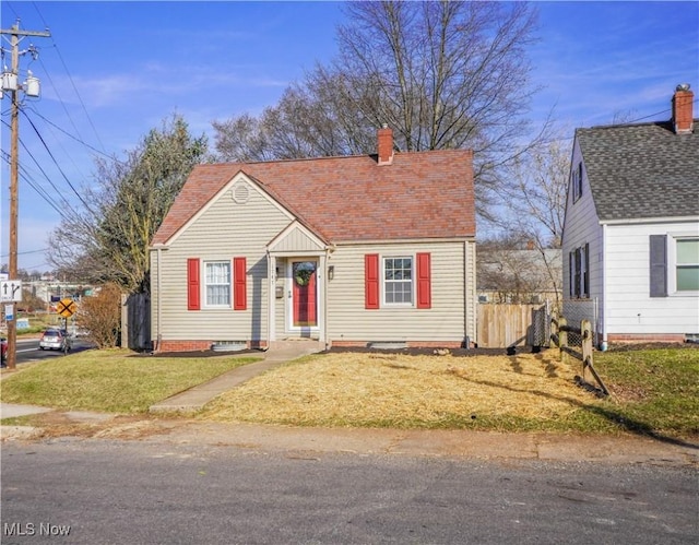 view of front of property with a front yard, fence, roof with shingles, and a chimney