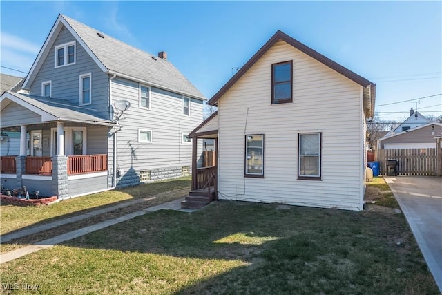 back of property featuring a porch, a lawn, and fence