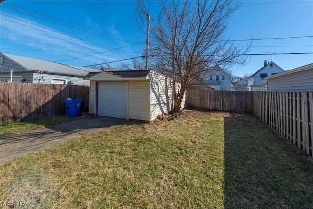 view of yard with aphalt driveway, a fenced backyard, a garage, and an outdoor structure