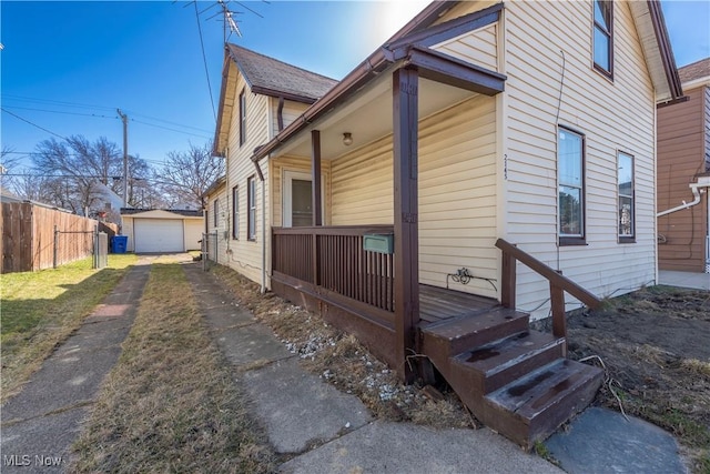 view of property exterior with driveway, a porch, fence, an outdoor structure, and a garage